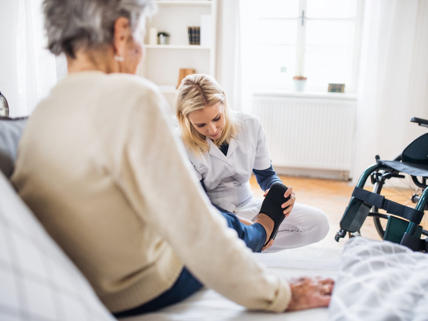 A SteadiCare caregiver helping an older woman put on her shoe at home