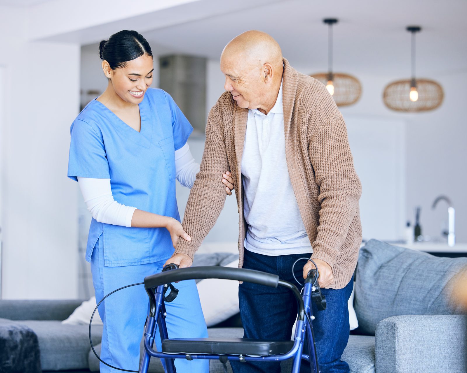 A SteadiCare caregiver steadying an older man as he walks with his walker at home