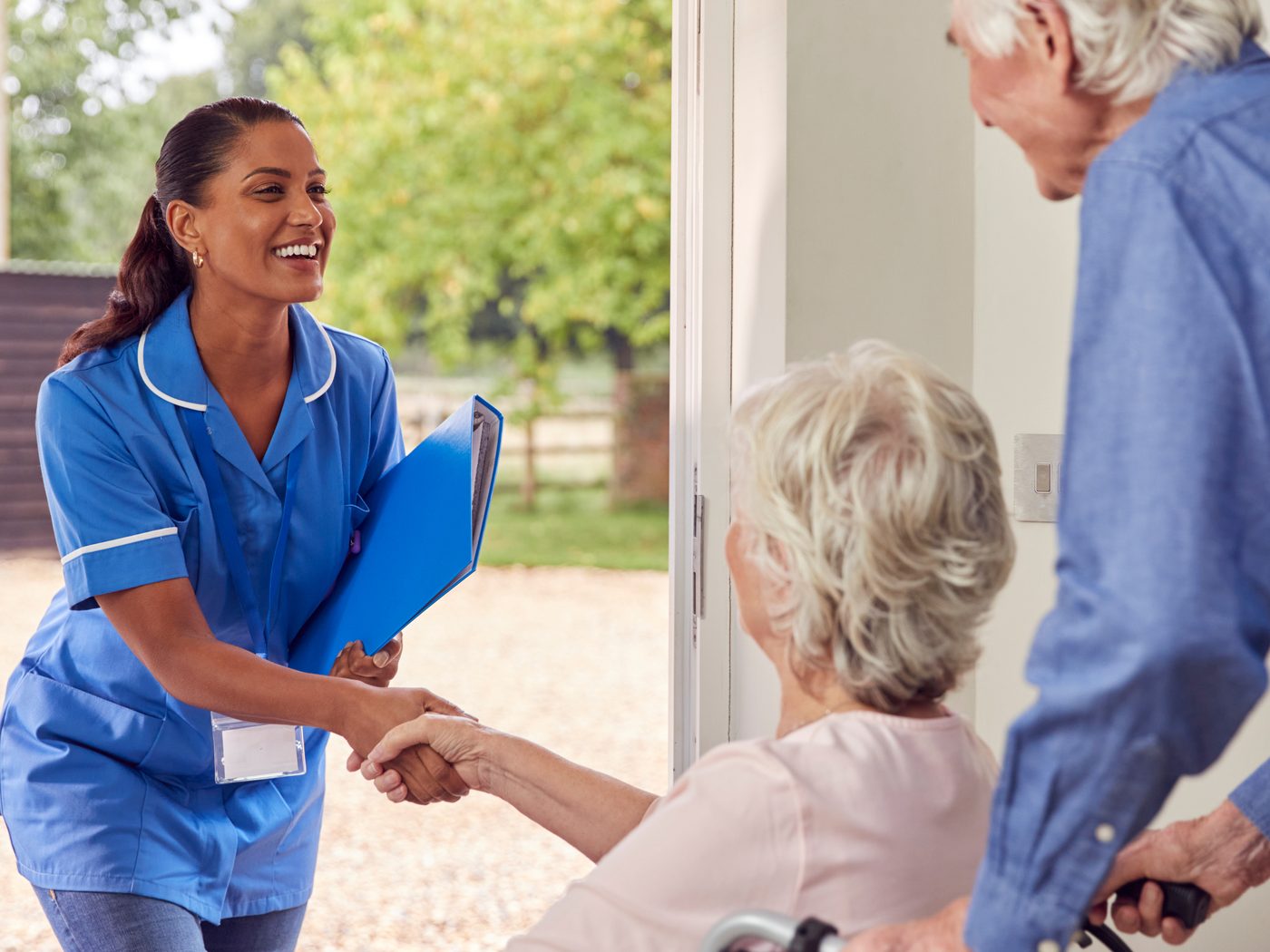 A SteadiCare caregiver being welcomed at the door by a senior couple