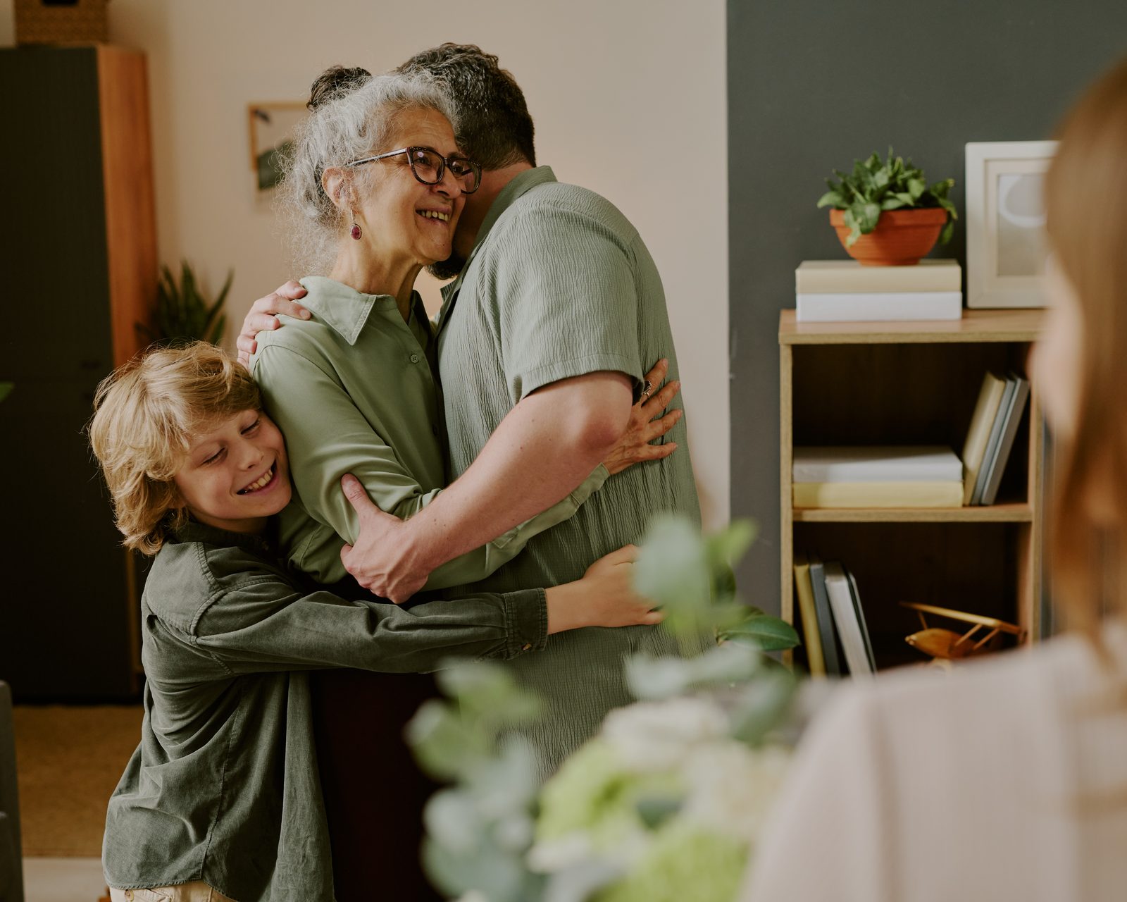 A grandmother home from the hospital, embraced by her son and grandson in the living room